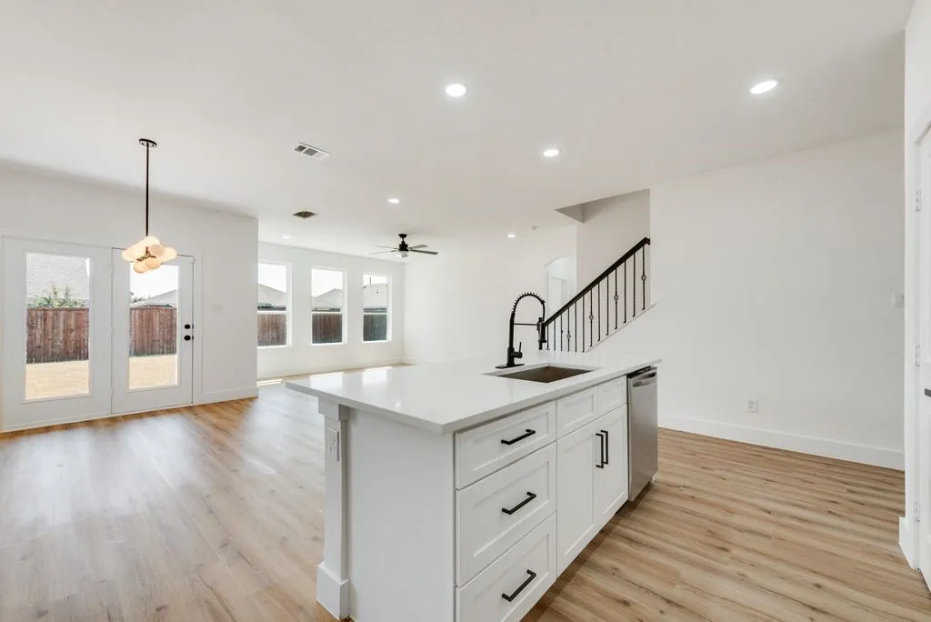 Kitchen island with a built-in sink and stainless steel dishwasher, wood-finish flooring, recessed lighting, and French doors