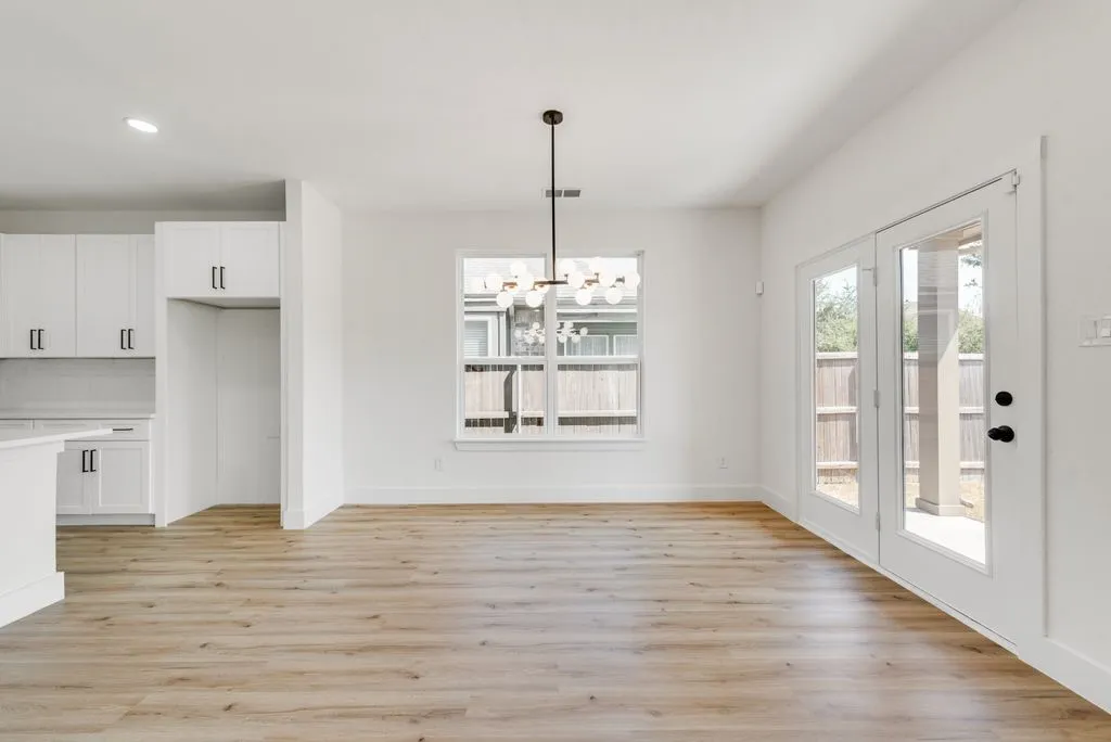 Wood-finish flooring throughout, white walls, and a modern chandelier