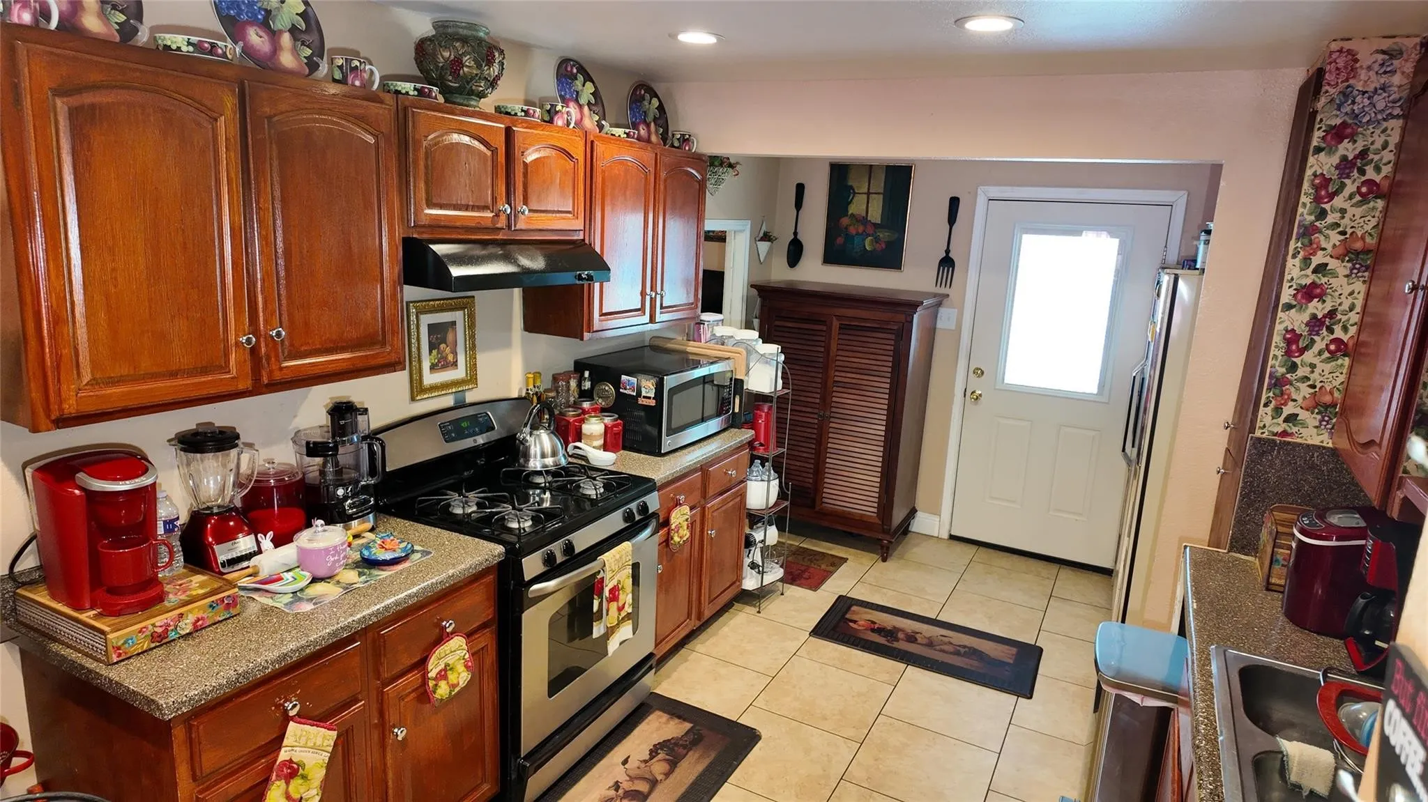 Kitchen featuring wood-finish cabinetry, a stainless steel gas range, tiled flooring, speckled countertops, and recessed lighting