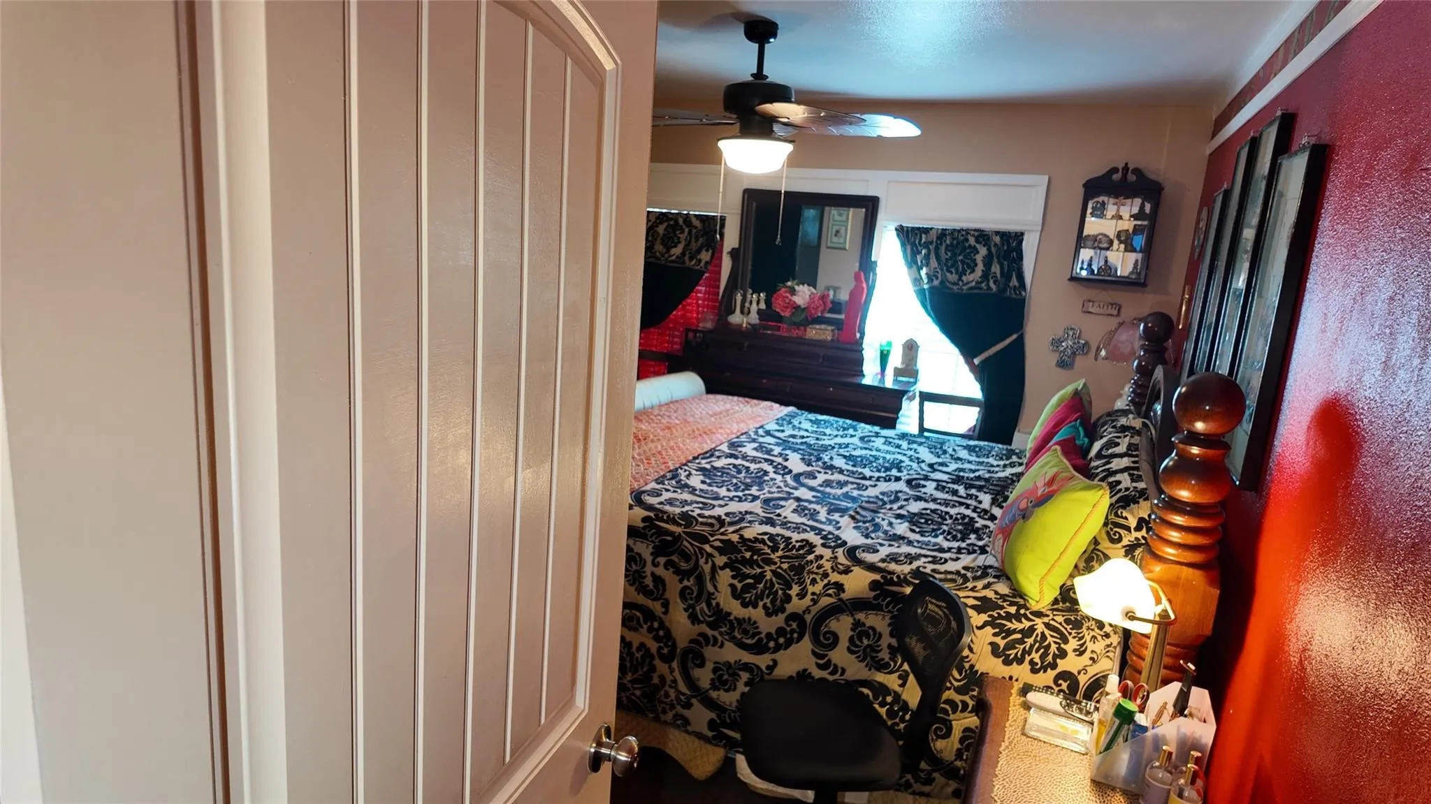 Paneled interior door, ceiling fan with light fixture, and a window with blinds