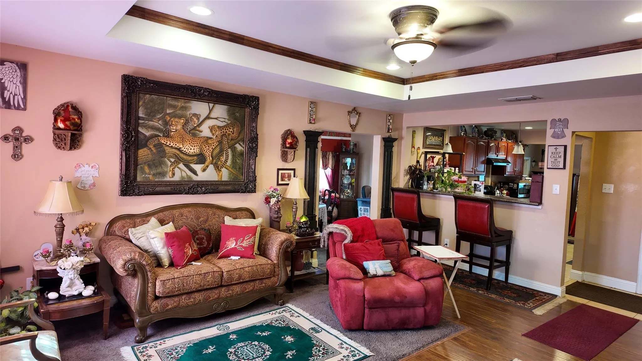 Tray ceiling with wood-finish trim, recessed lighting, and a ceiling fan