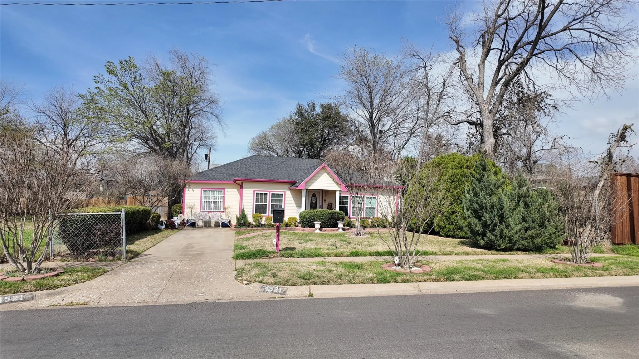 Single-story residence featuring a paved driveway, front lawn, and mature trees