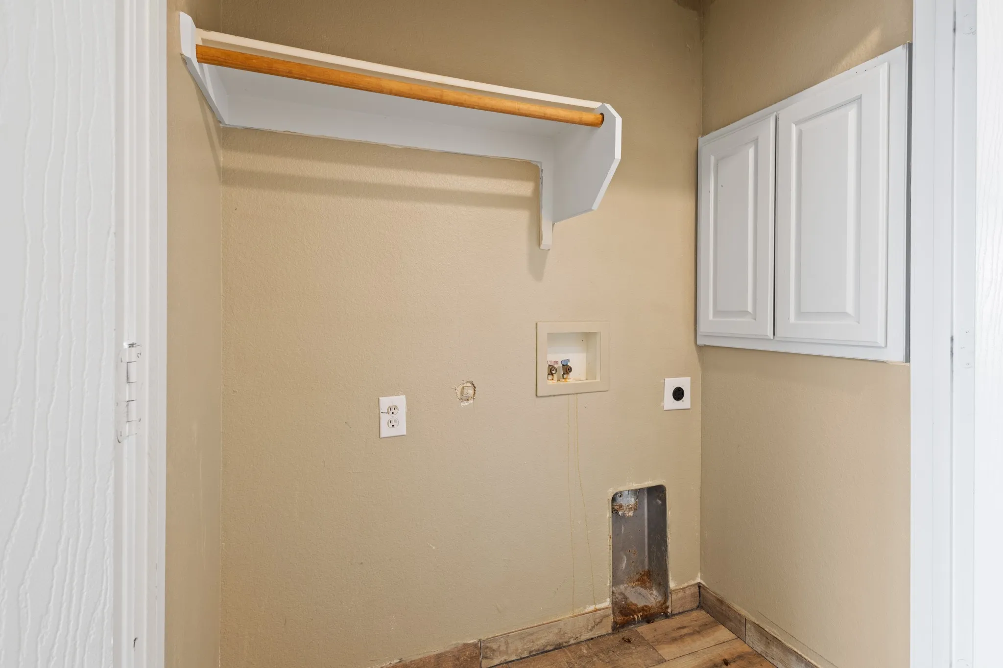 Utility area with overhead shelving, a hanging rod, and wall-mounted cabinetry