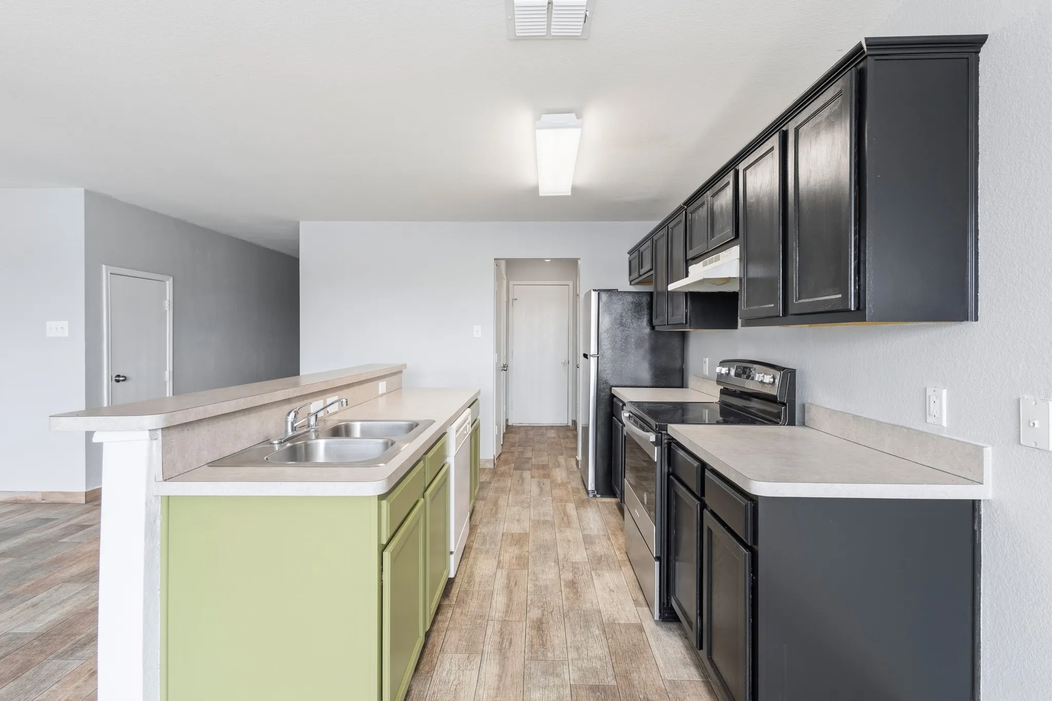 Kitchen featuring wood-finish flooring, two-tone cabinetry, laminate countertops, and a double basin stainless steel sink