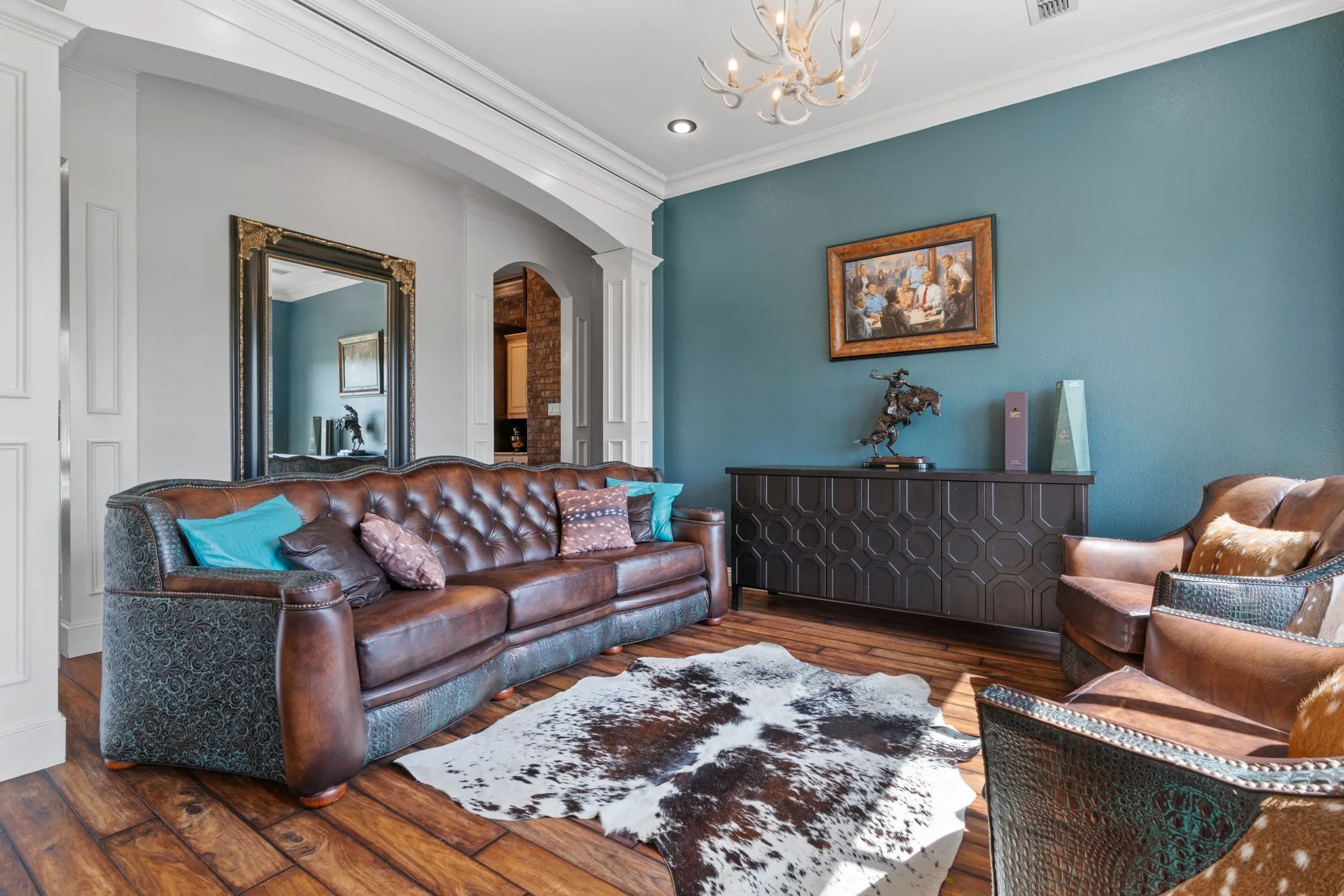 Wood-finish flooring, decorative wall paneling, crown molding, arched entryway, and a built-in credenza