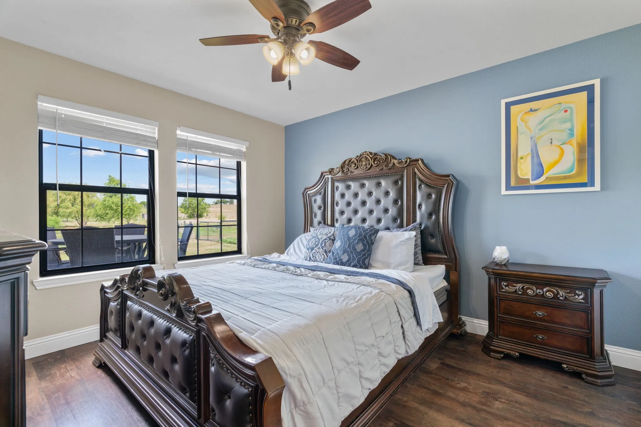 GUEST HOUSE! Warm interior paint tones, dark wood-finish flooring, two large windows, and a ceiling fan with integrated lighting