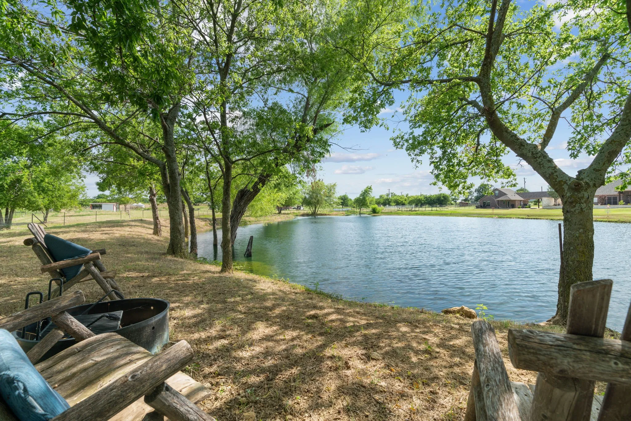 Expansive private pond with a naturalized shoreline, framed by mature trees, offering a serene outdoor setting