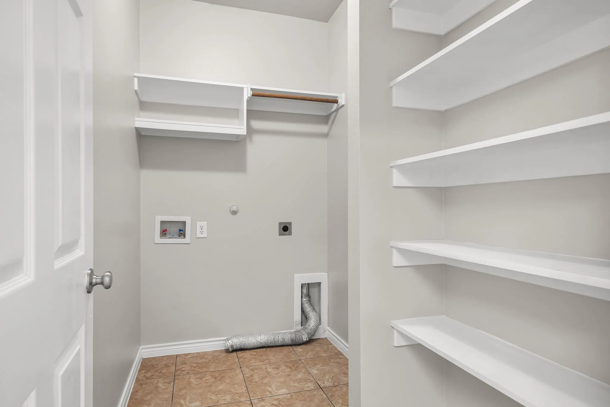 Laundry area with tiled flooring, built-in shelving, and a hanging rod