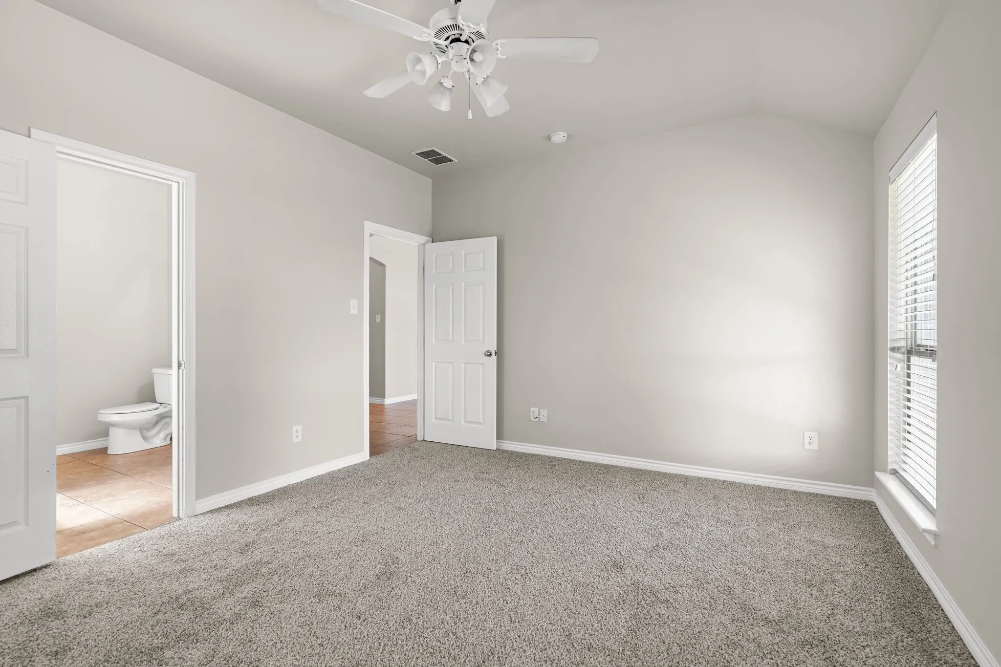 Vaulted ceiling, ceiling fan, neutral carpet flooring, window with blinds, and white interior doors