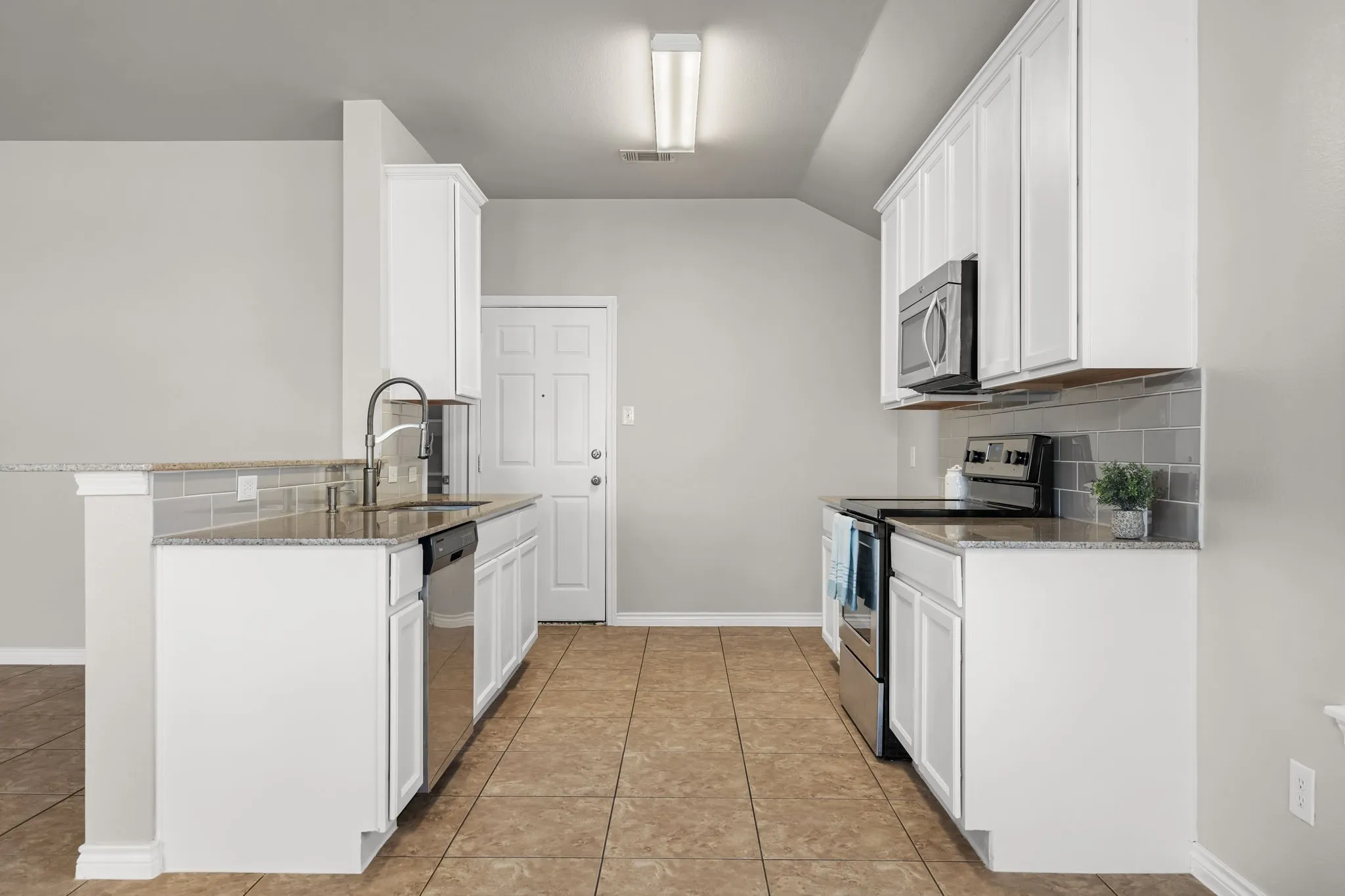 Kitchen featuring white cabinetry, stainless steel appliances, granite countertops, and a subway tile backsplash