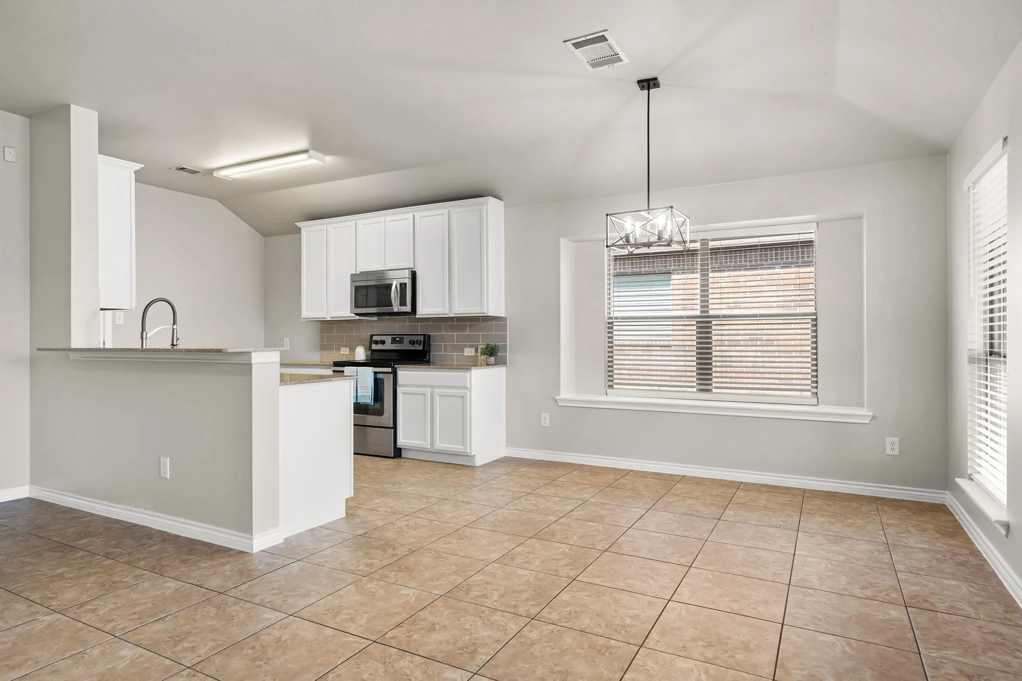 Kitchen featuring white cabinetry, stainless steel appliances, a gray subway tile backsplash, and a breakfast bar
