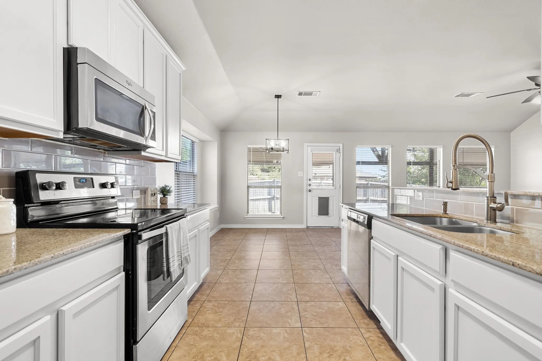 Kitchen featuring white cabinetry, stainless steel appliances, tile flooring, and a subway tile backsplash