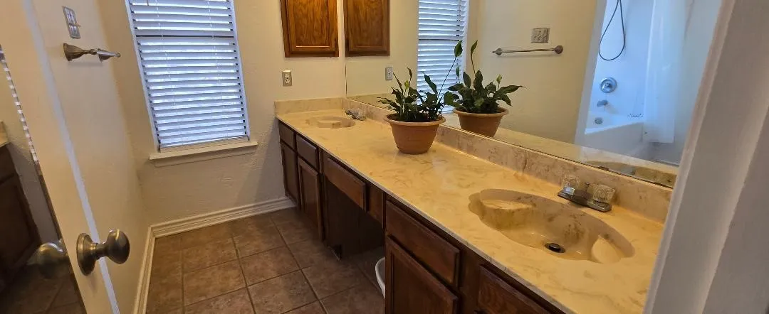 Dual sink vanity with integrated sinks, stone-look countertop, and wood-finish cabinetry