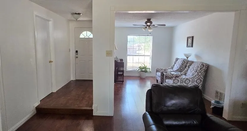 Wood-finish flooring throughout, white interior doors, and a front entry door with an arched window