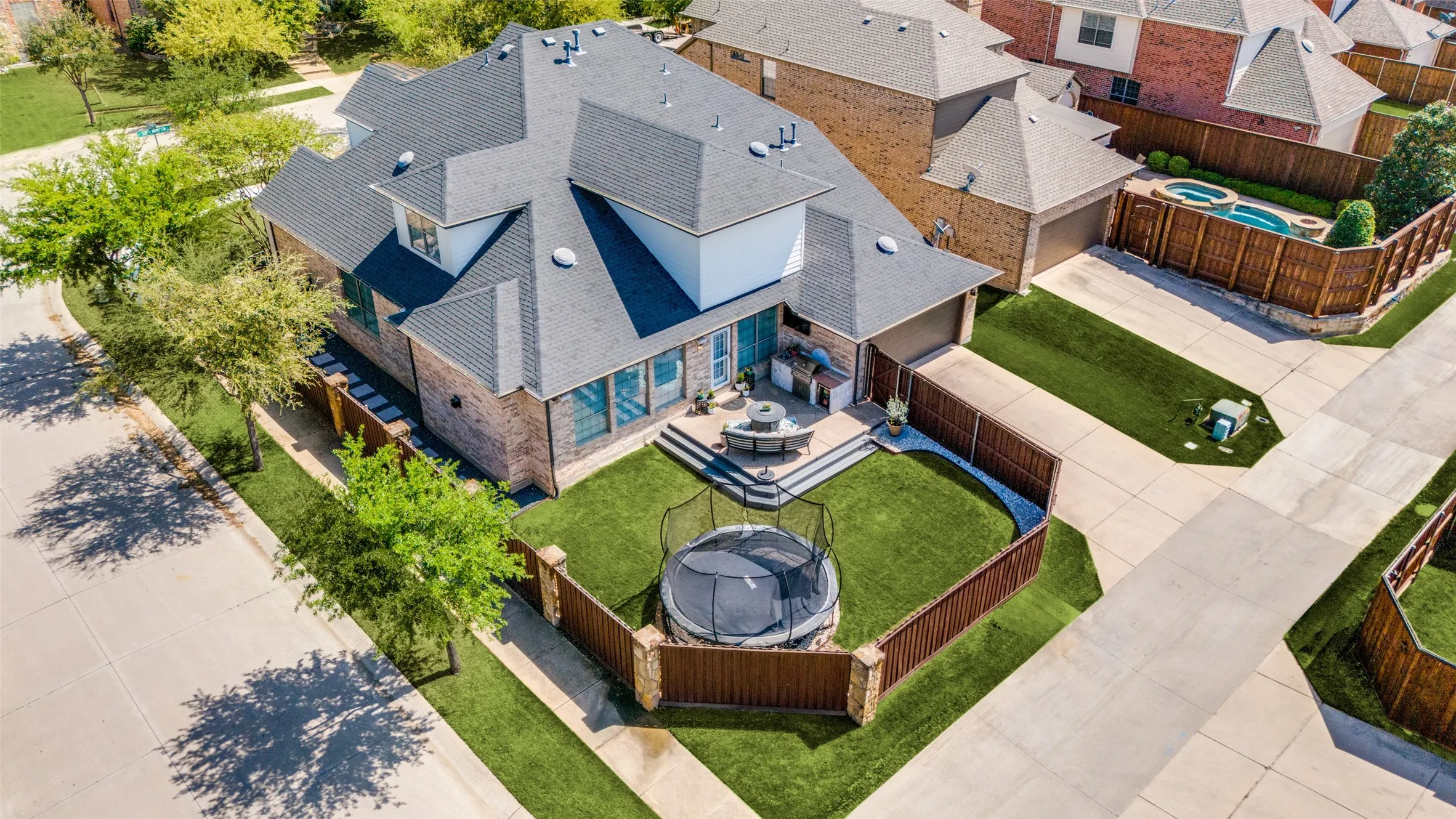Expansive backyard featuring a manicured lawn, raised patio, and privacy fencing