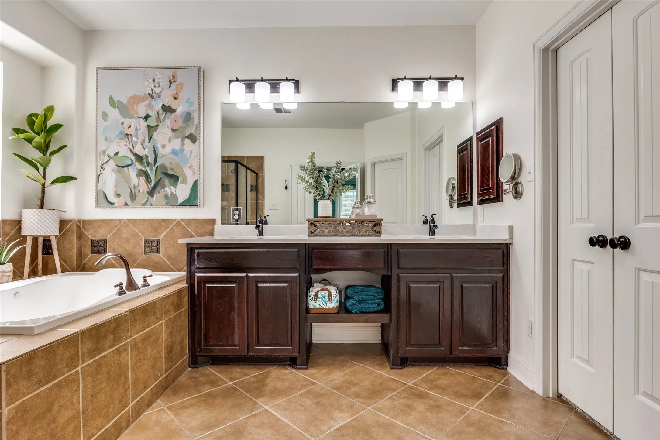 Dual vanity with dark wood-finish cabinetry, white countertop, and individual mirrors with contemporary lighting fixtures