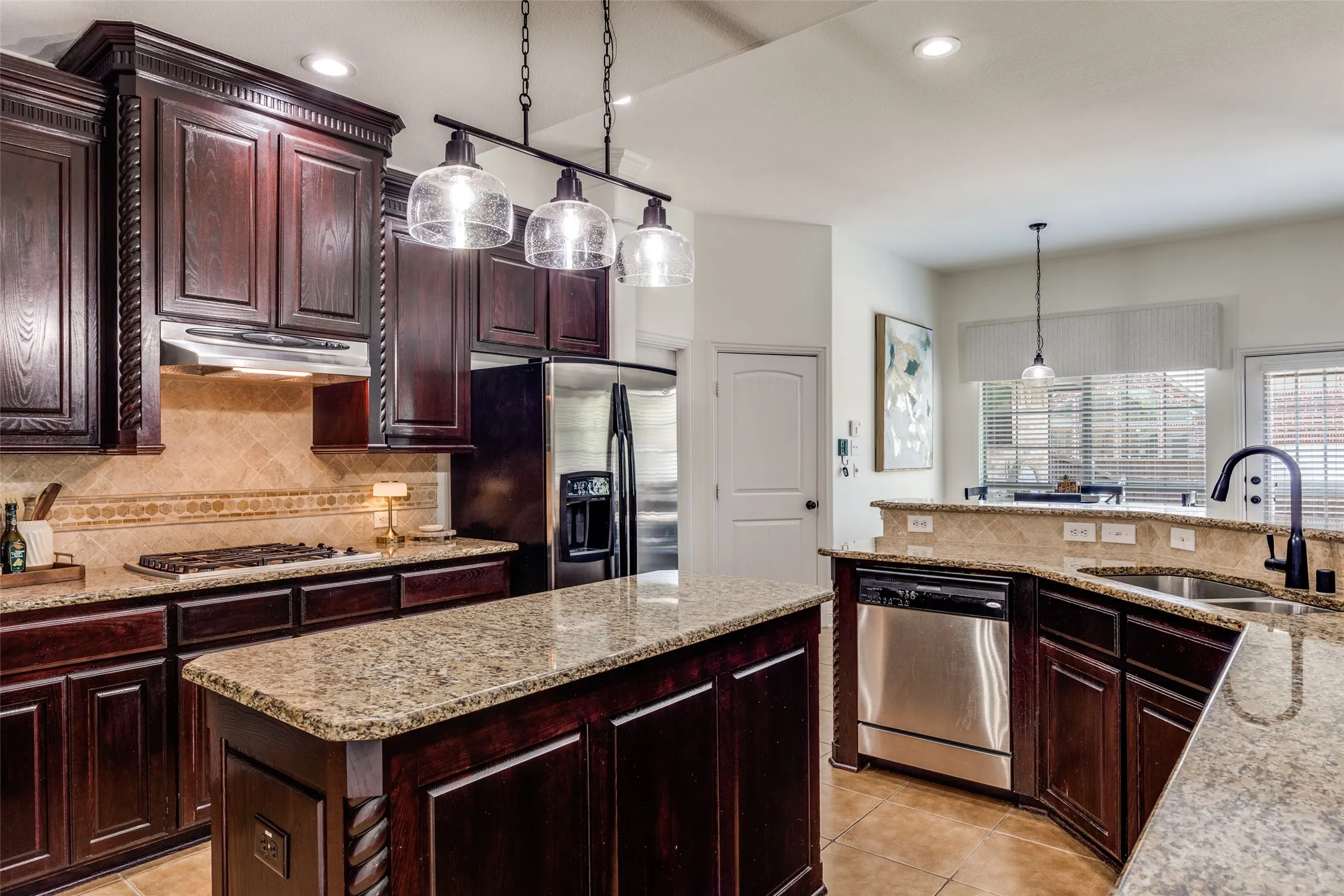 Kitchen featuring dark wood cabinetry, light granite countertops, stainless steel appliances, a center island, and a tile backsplash