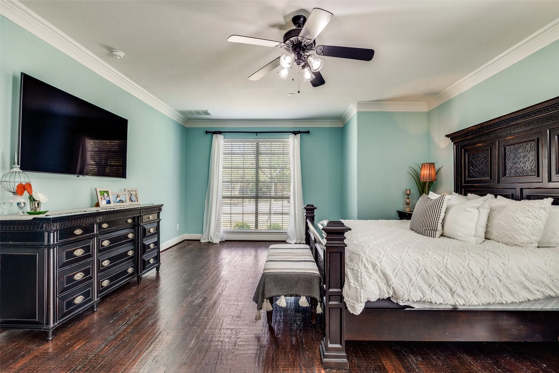 Wood-finish flooring with crown molding and a ceiling fan