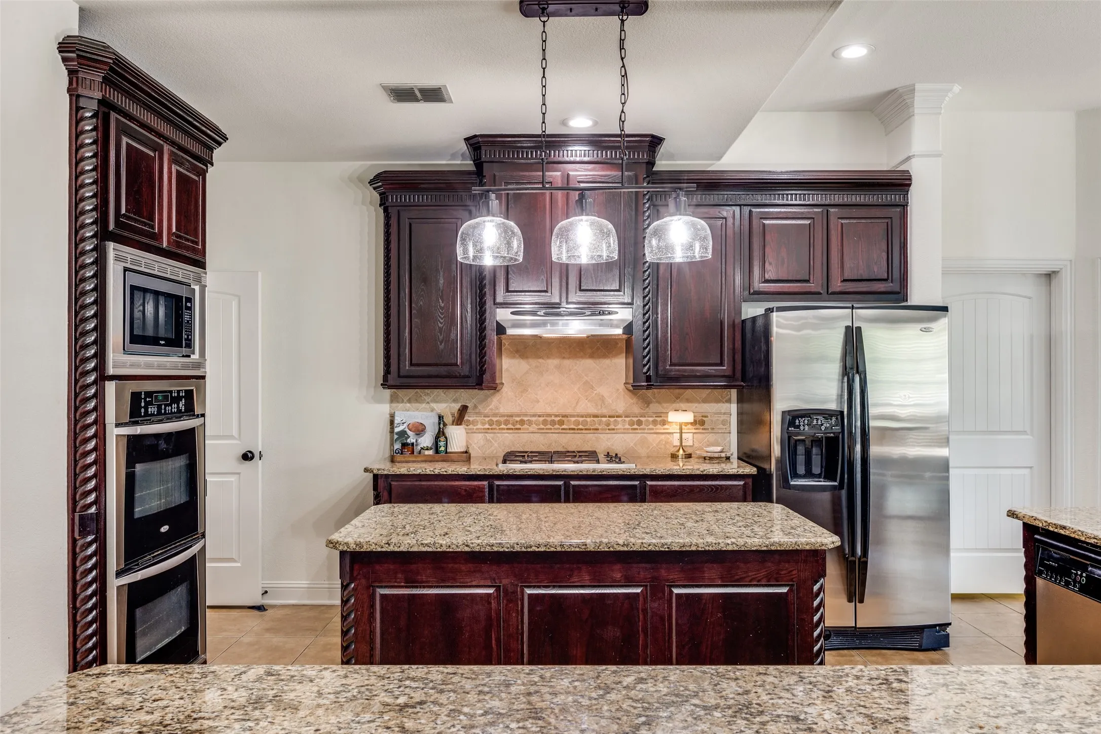Kitchen featuring dark wood-finish cabinetry, granite countertops, stainless steel appliances, and a tiled backsplash