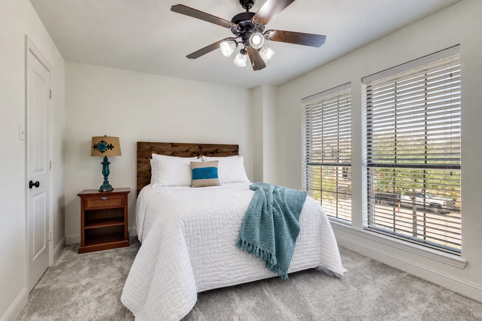 Bright room with two large windows, a ceiling fan with integrated lighting, and light-colored carpeting