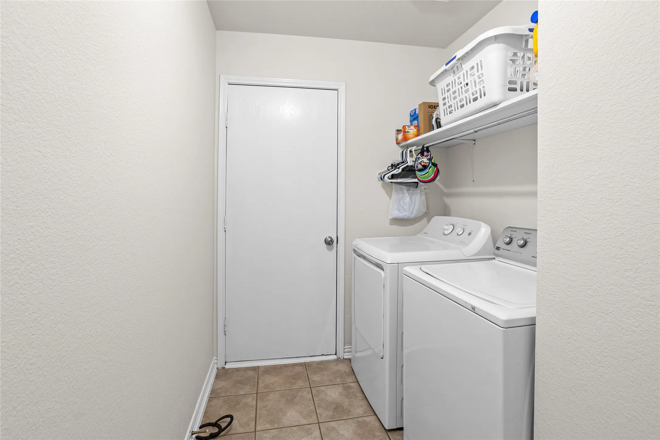 Laundry area featuring ceramic tile flooring and built-in shelving