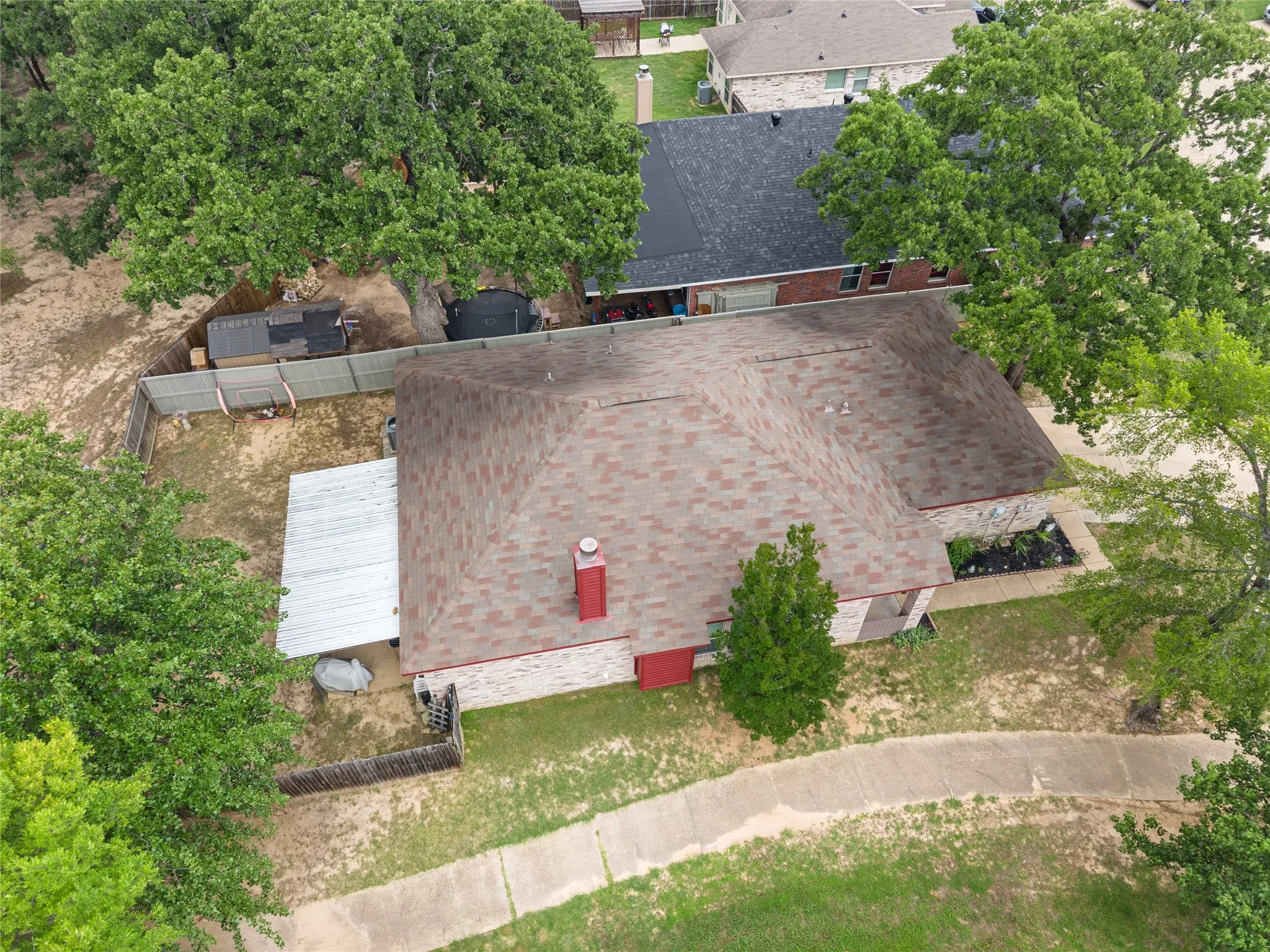 Asphalt shingle roof, chimney, concrete walkway, fenced backyard, mature trees