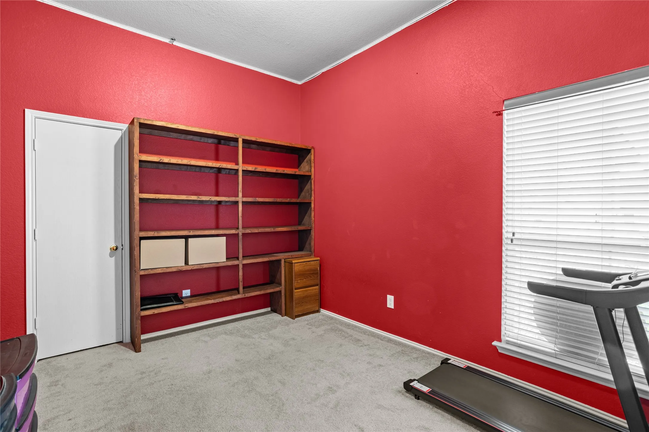 Built-in shelving with integrated drawer storage, bright wall finish, and window with blinds