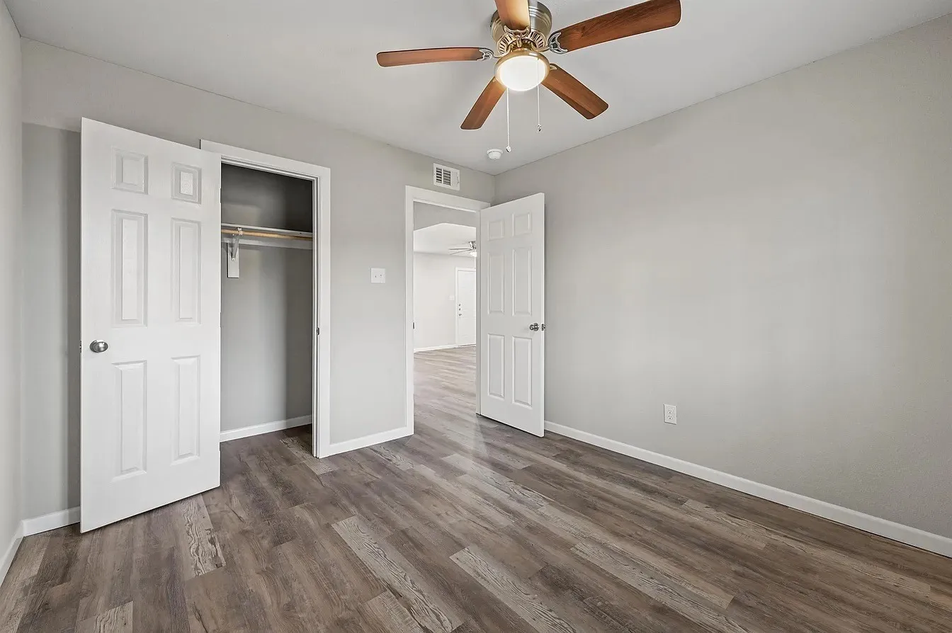 Wood-finish flooring throughout, white paneled doors, and a ceiling fan with light fixture