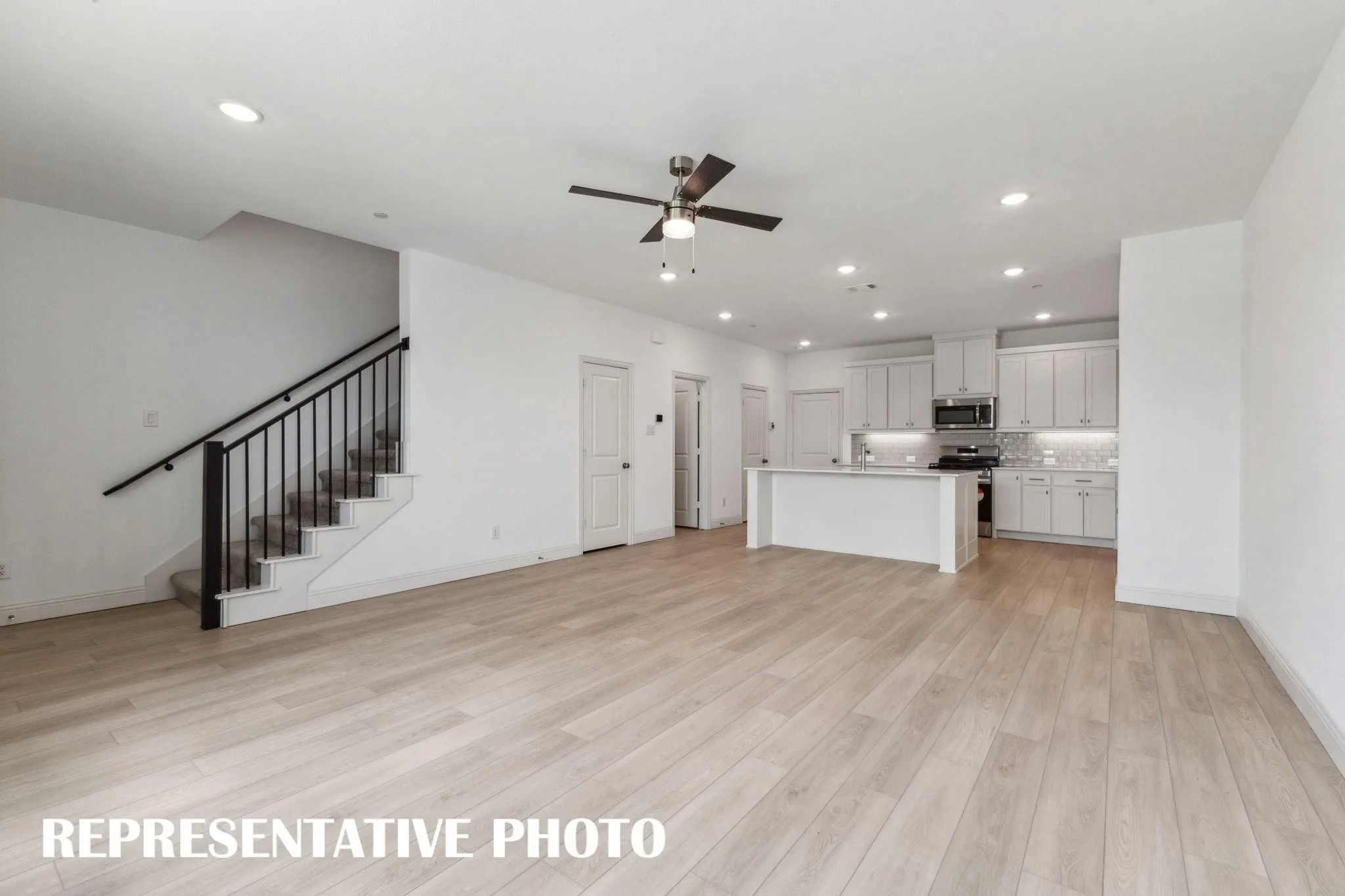 Open-concept living space featuring wood-finish flooring, a kitchen island with seating, stainless steel appliances, and recessed lighting