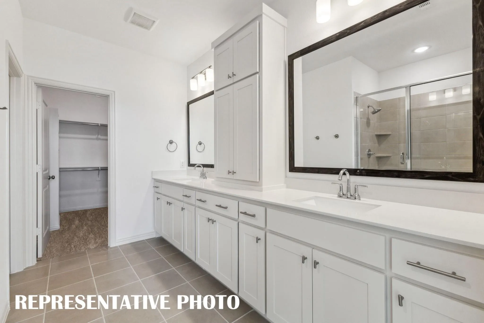 Dual vanity with white cabinetry, integrated sinks, chrome fixtures, and a glass-enclosed shower