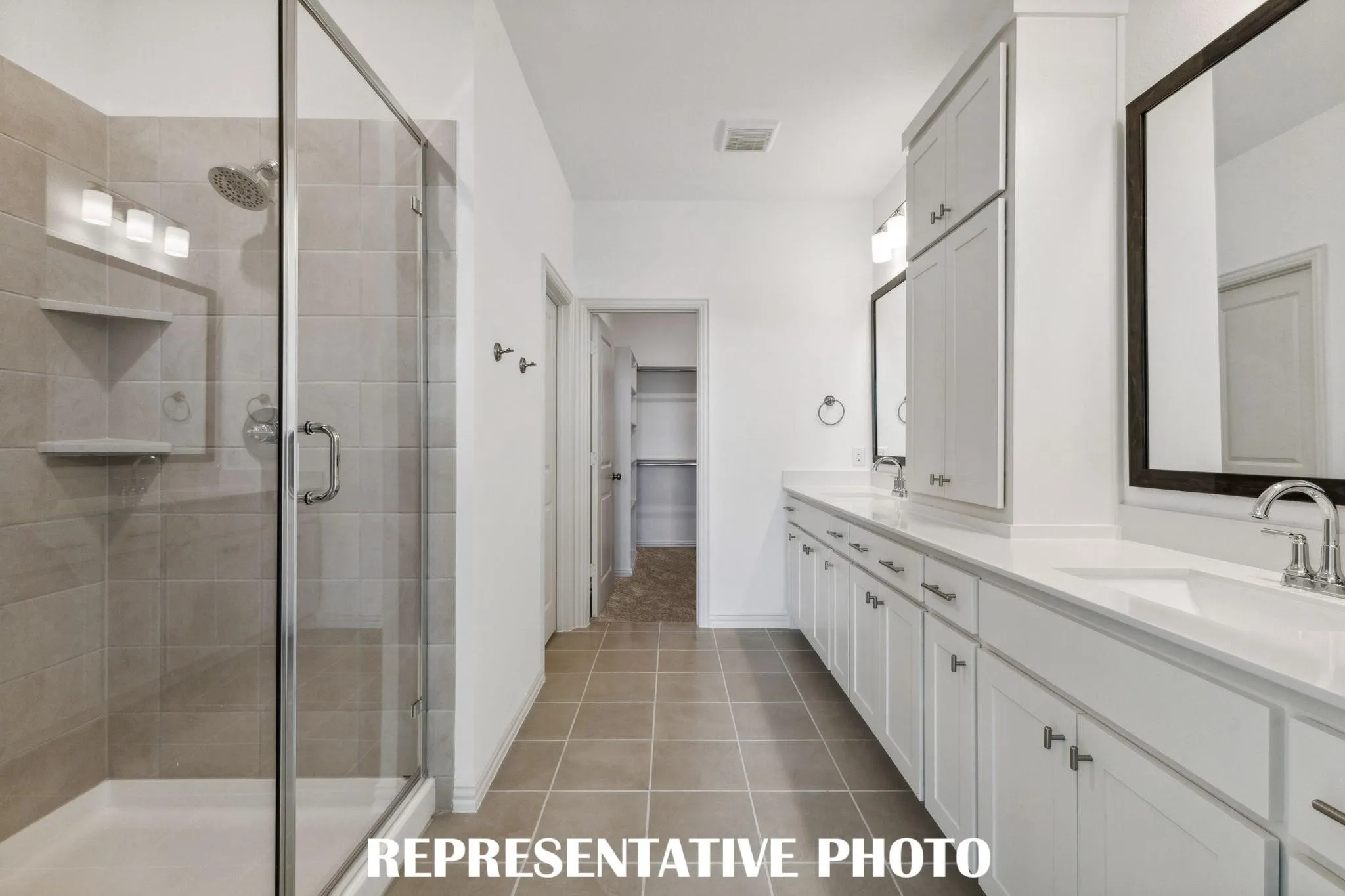 Walk-in shower with glass enclosure, dual vanity with white cabinetry, square undermount sinks, and tile flooring