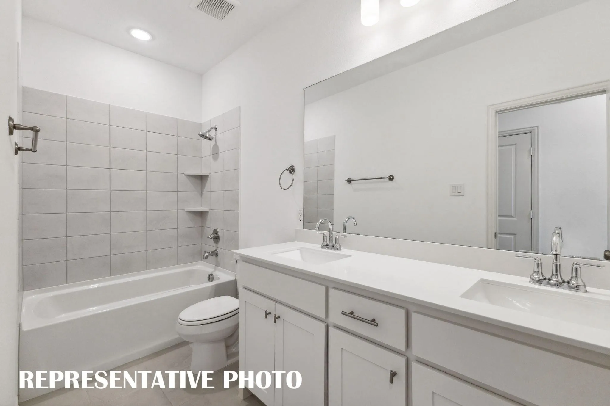Dual vanity with integrated sinks, white cabinetry, and a large wall-mounted mirror