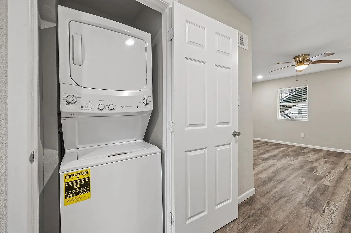 Built-in stacked washer and dryer, wood-finish flooring, ceiling fan with light fixture, recessed lighting, and panel door