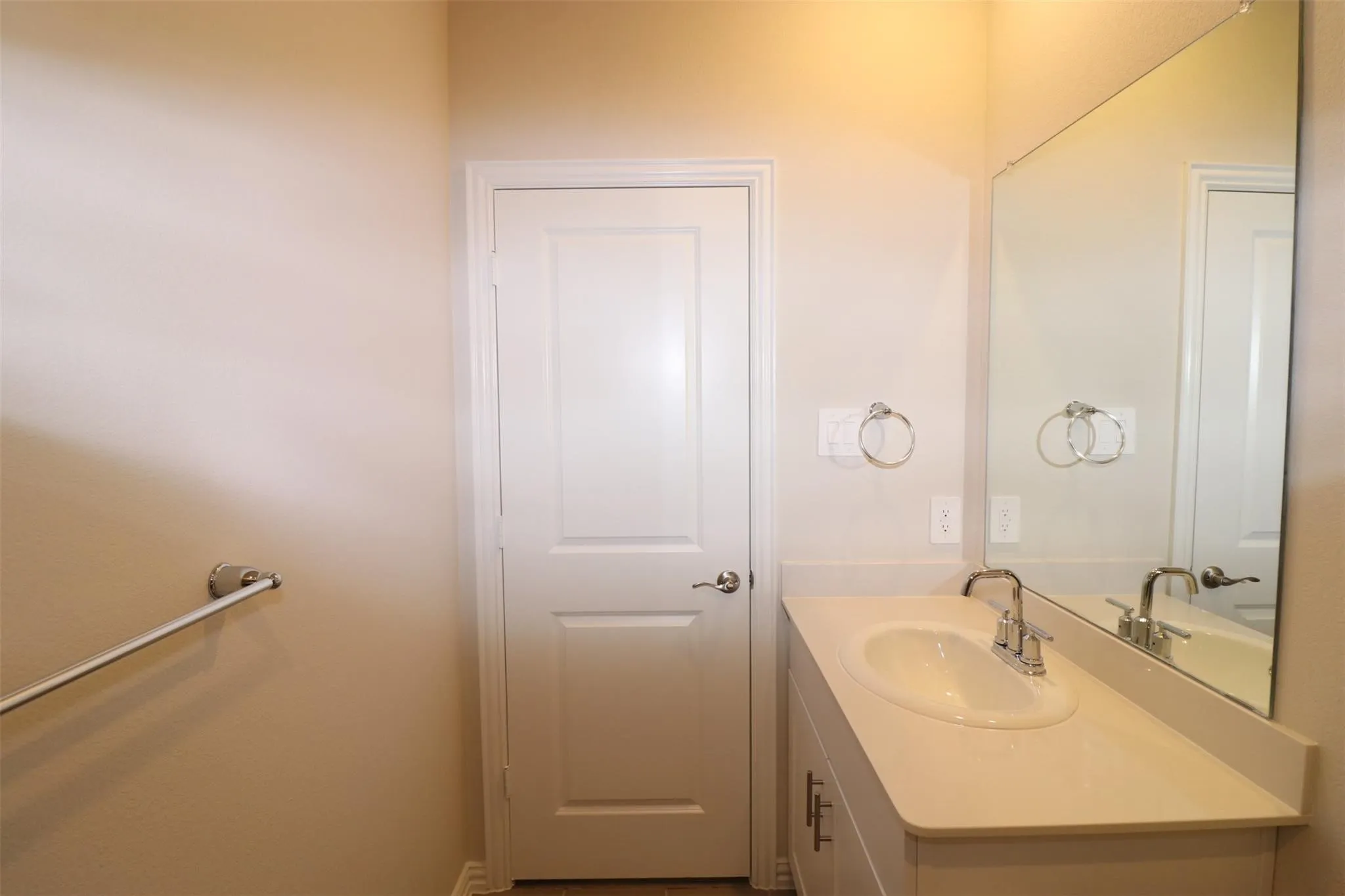 Bathroom vanity with an integrated sink, polished chrome faucet, and expansive wall-mounted mirror