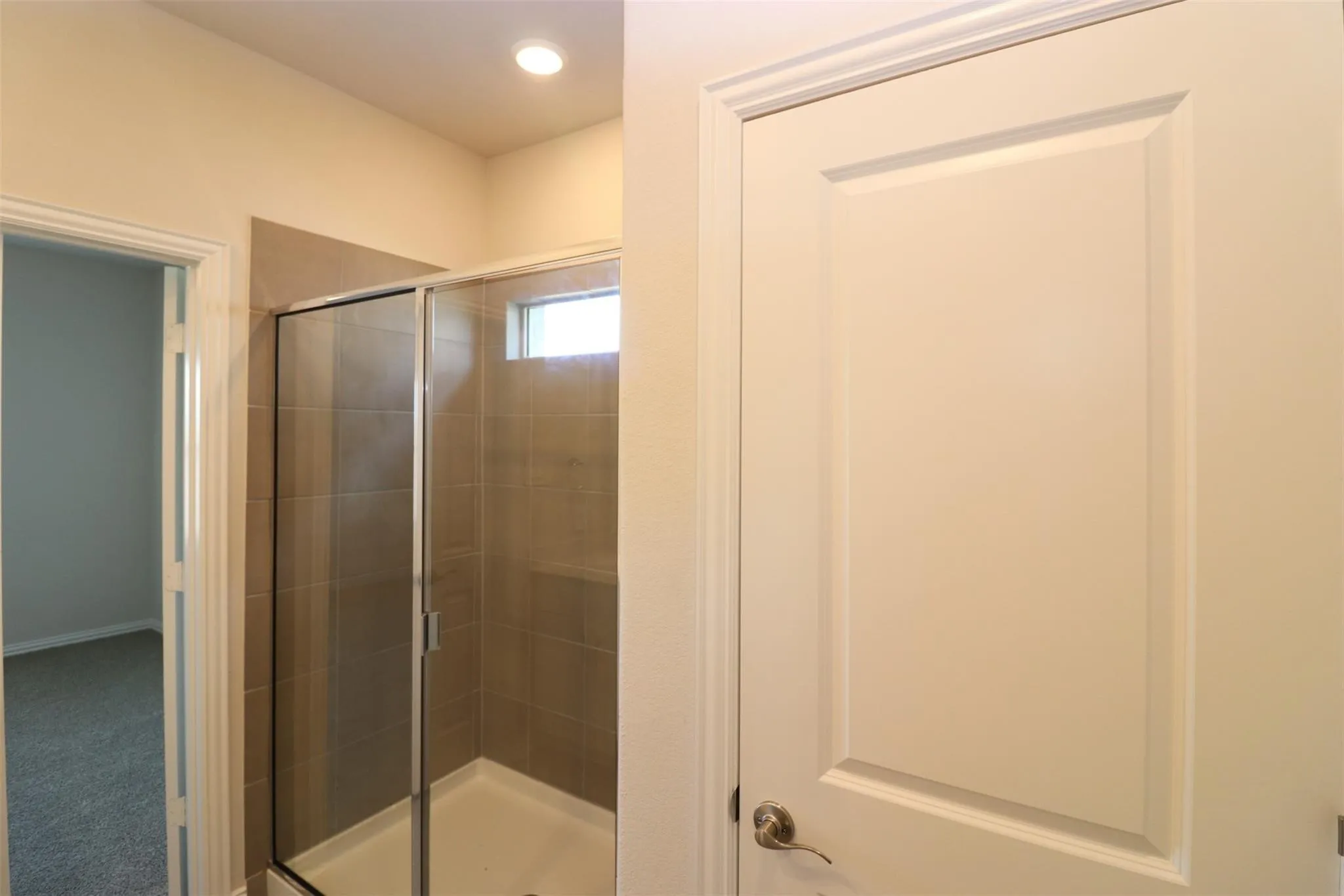 Walk-in shower with full-height tile surround, glass enclosure, and transom window