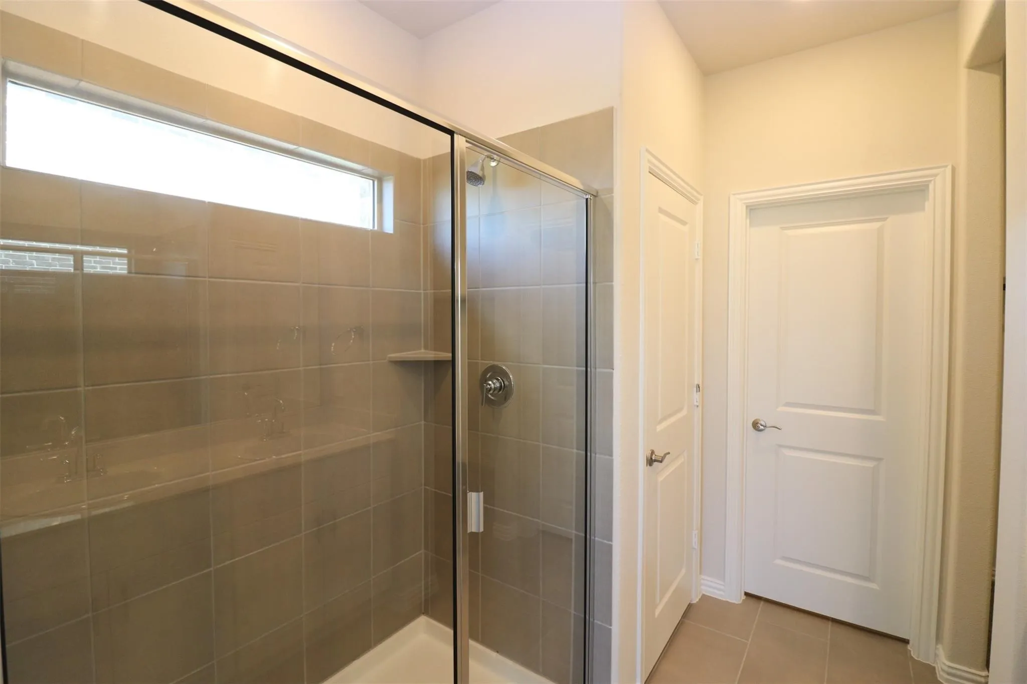 Glass-enclosed shower with a built-in bench, tiled walls, and a transom window