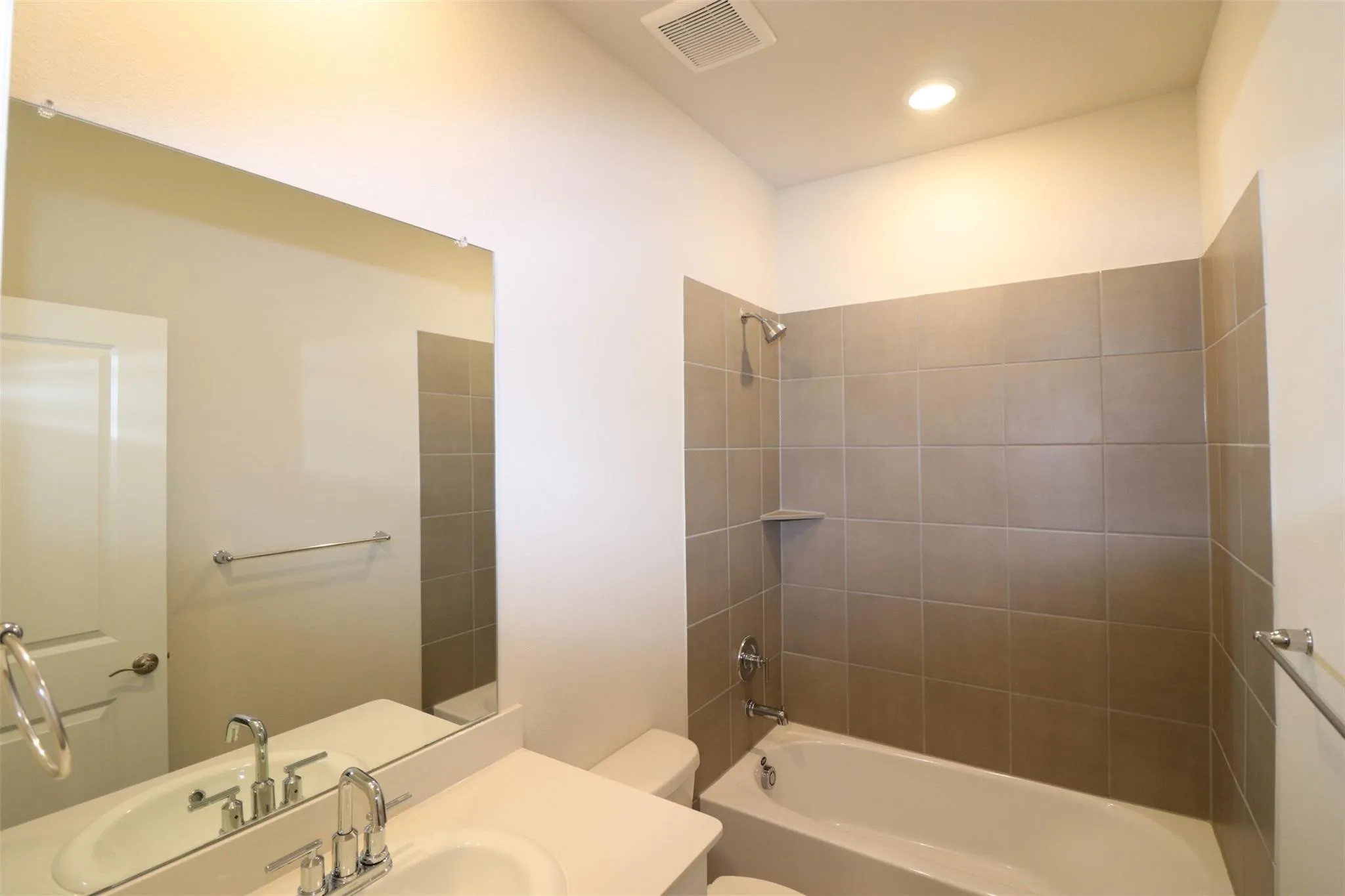 Bathroom featuring a neutral tile shower surround, integrated shower niche, and a vanity with a rectangular sink