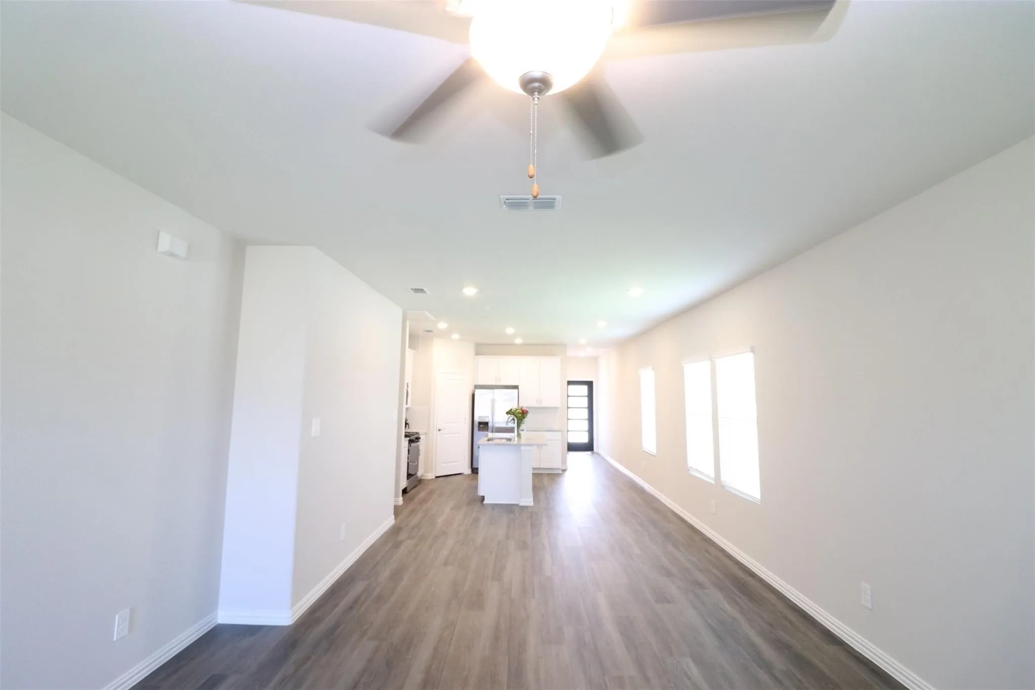 Recessed lighting, wood-finish flooring, ceiling fan, multiple windows, and a kitchen island with built-in cabinetry