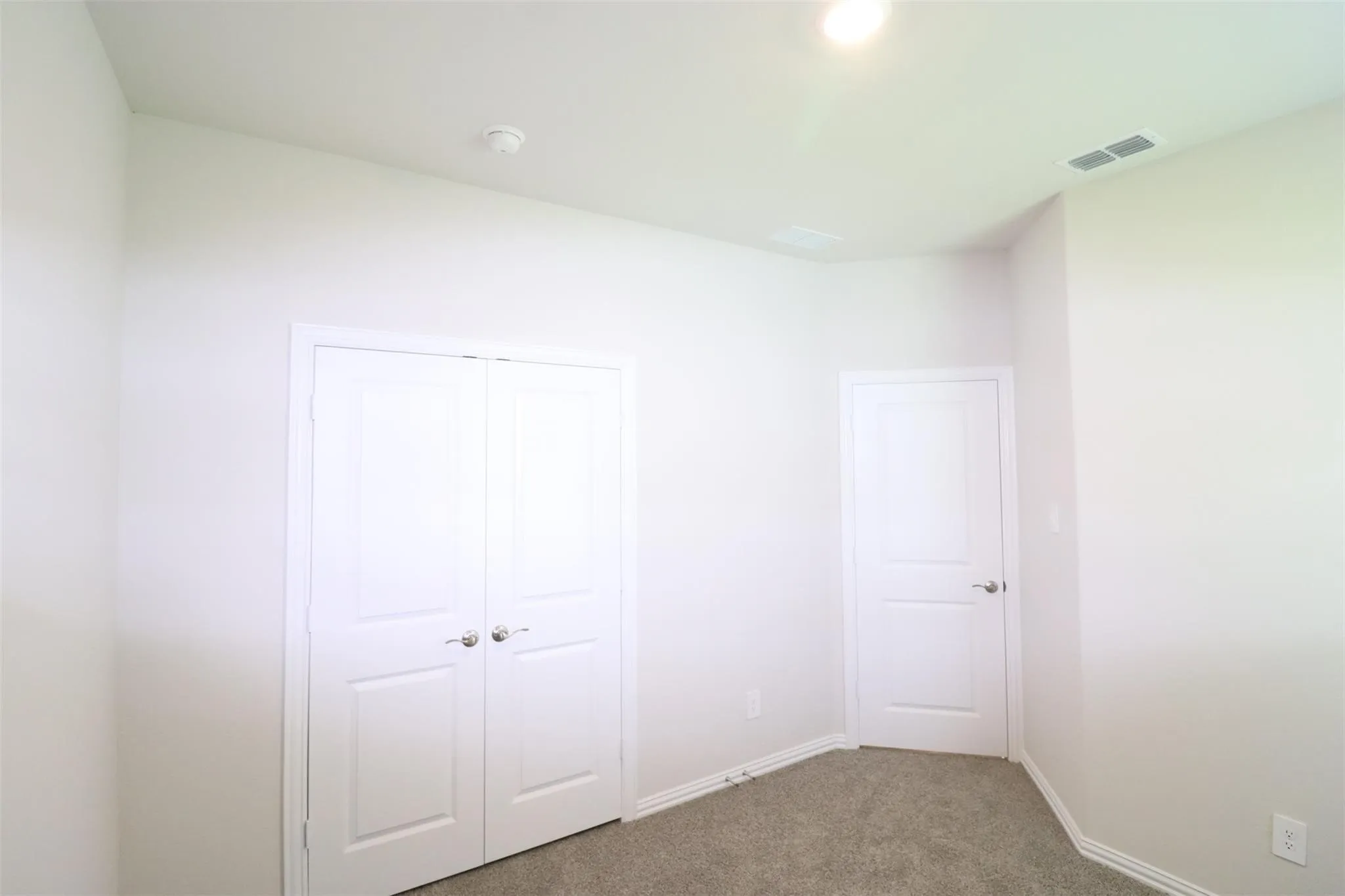 White interior doors, neutral wall paint, recessed lighting, and grey carpeting