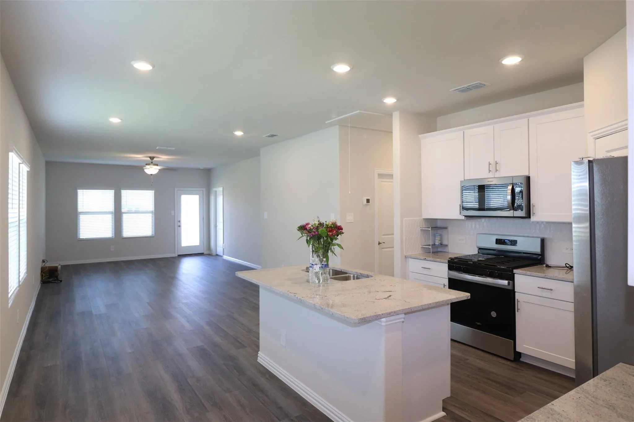 Open-concept living space with wood-finish flooring, recessed lighting, and a ceiling fan