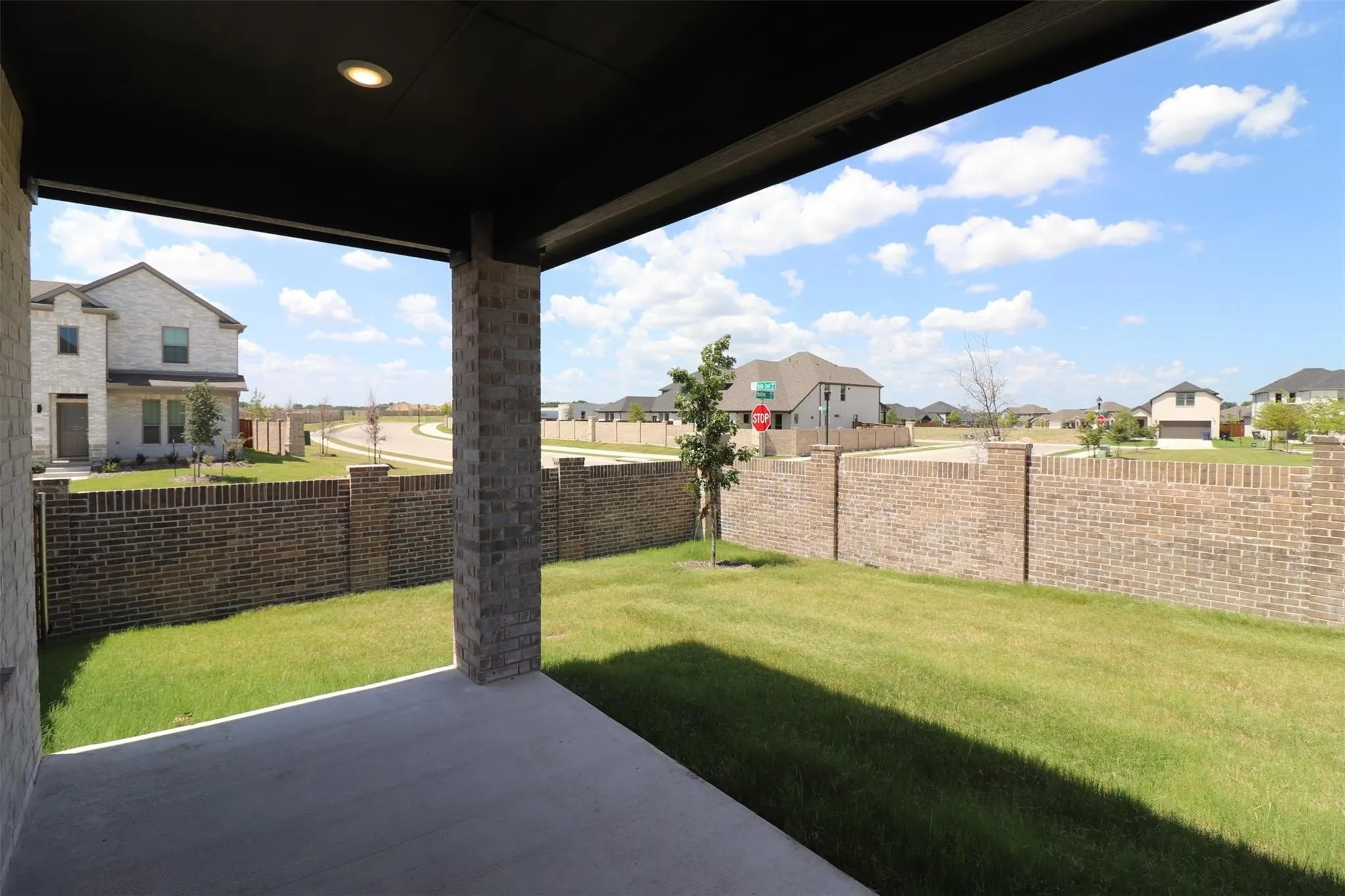 Covered patio with recessed lighting, brick columns, and a concrete surface