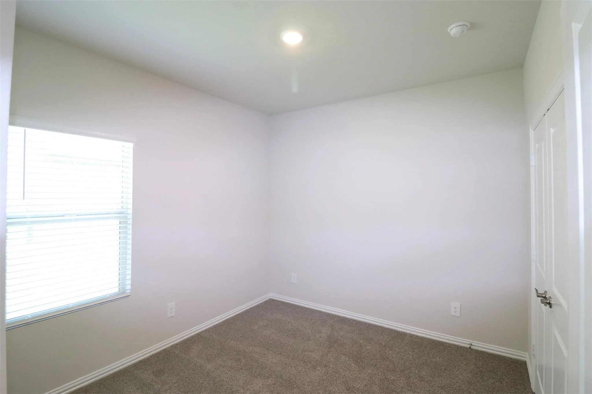 Carpeted room with a single window, recessed lighting, and a white paneled door