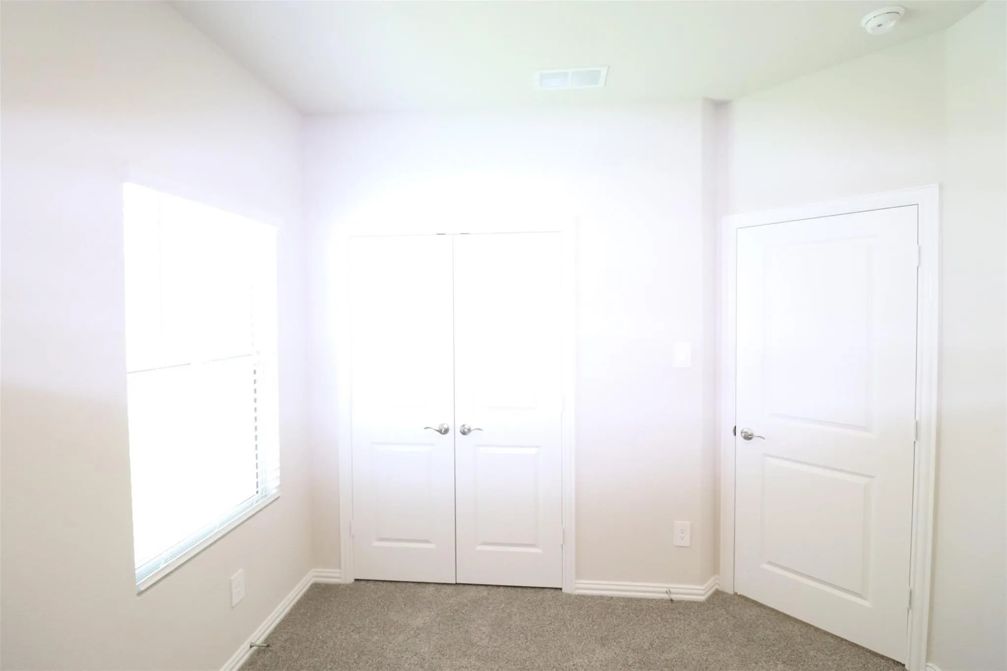Neutral tone wall paint, carpet flooring, window with blinds, recessed ceiling light, and panel doors