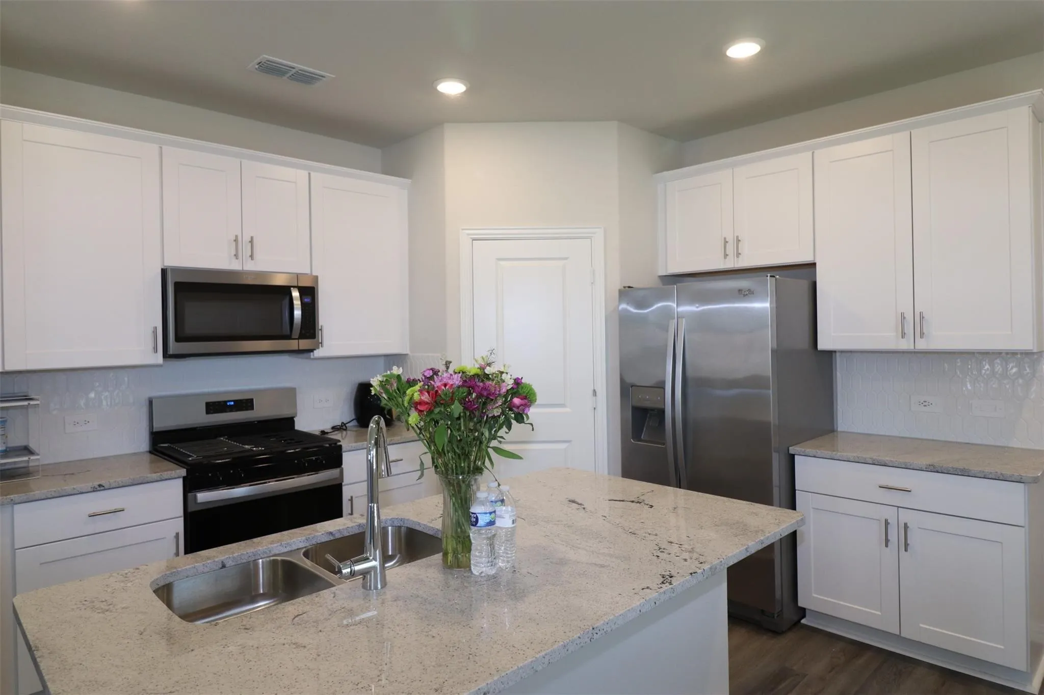 Kitchen featuring white cabinetry, stainless steel appliances, granite countertops, and wood-finish flooring