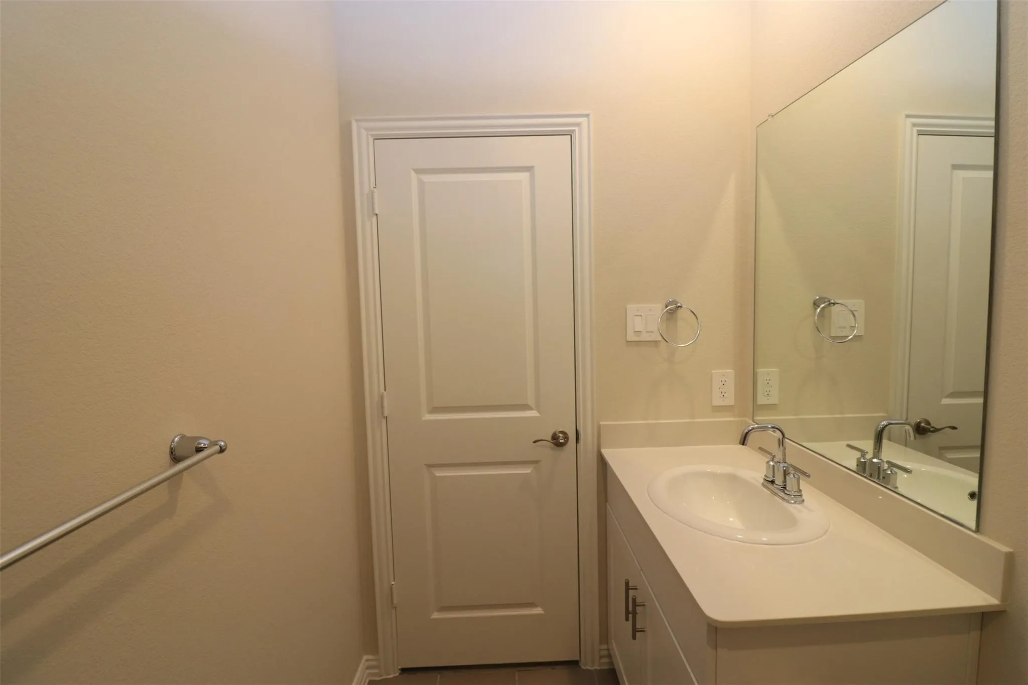 Single vanity with an integrated sink, polished chrome faucet, and a large wall-mounted mirror