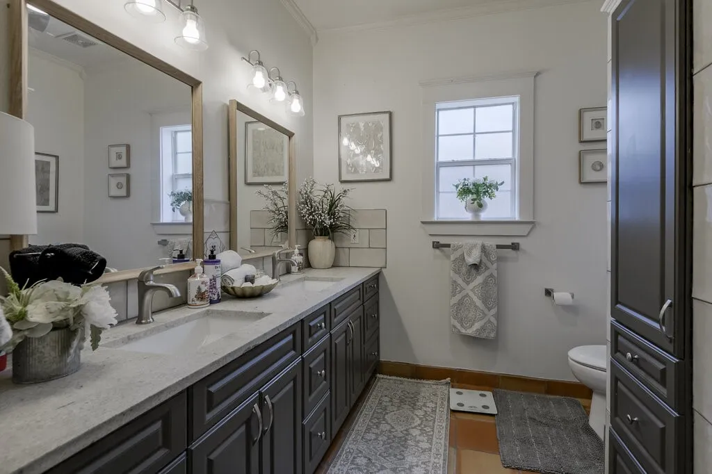Spa-inspired primary bathroom featuring a double-sink vanity with charcoal cabinetry, marble countertops, and polished chrome fixtures