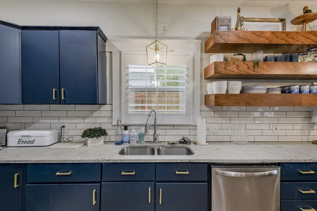 Contemporary kitchen featuring custom navy cabinetry with brushed gold hardware, subway tile backsplash, and white quartz countertops