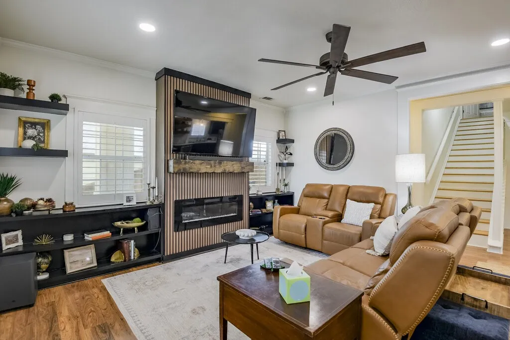 Integrated media wall with an electric fireplace, wood-finish flooring, recessed lighting, and a ceiling fan