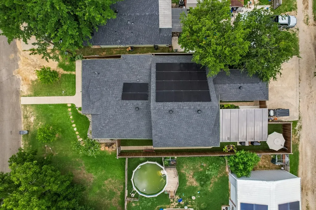 Asphalt shingle roof, integrated solar panels, fenced yard, concrete patio, mature trees