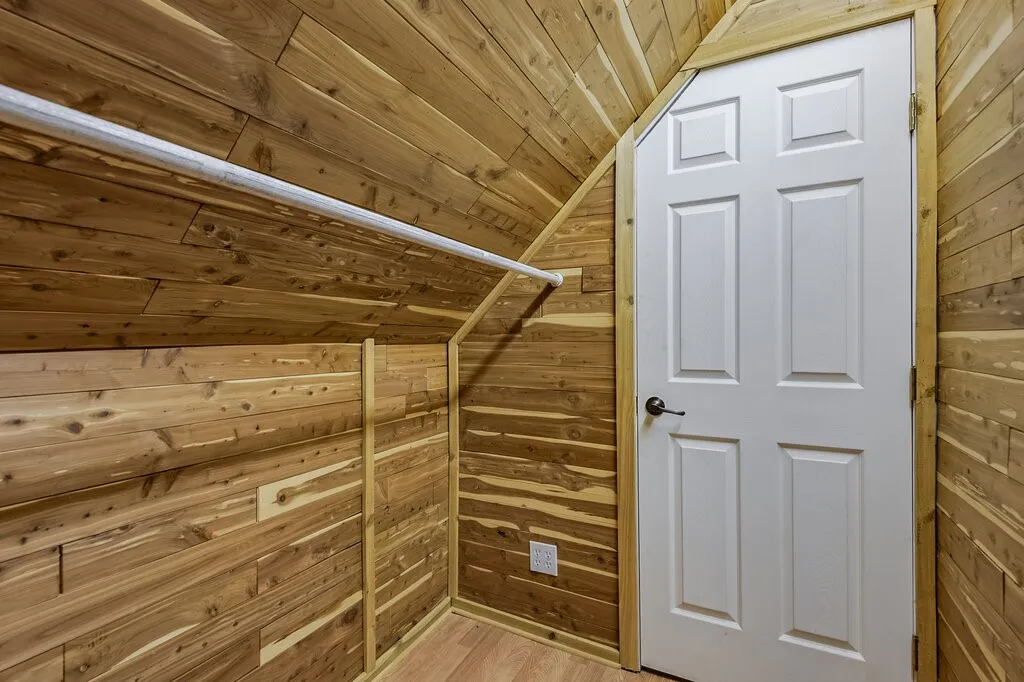 Finished Interior Space with Tongue-and-Groove Wood Paneling, Recessed Lighting, Six-Panel White Door, and Electrical Outlet
